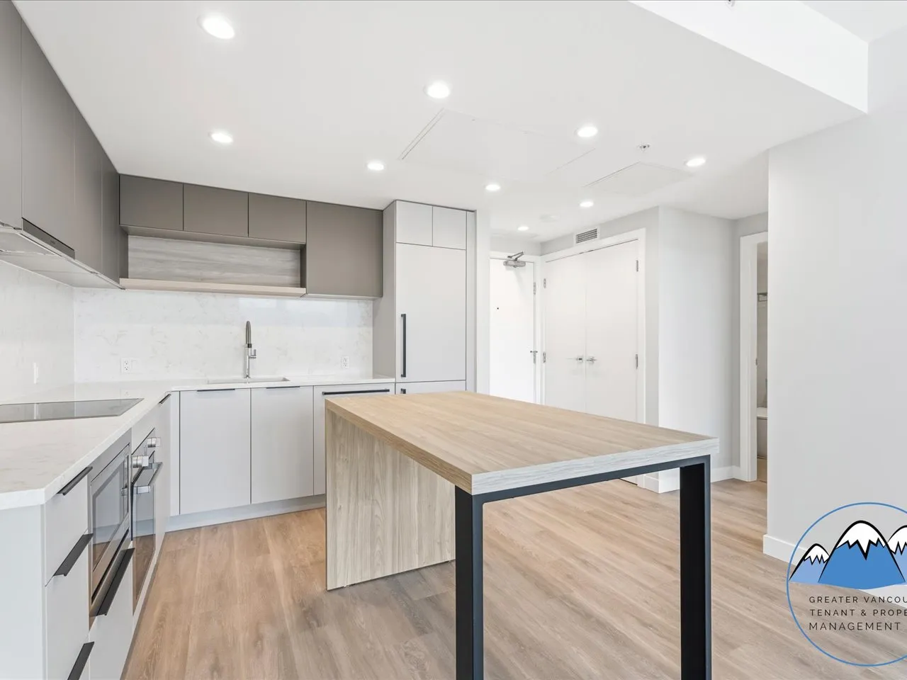 Open-concept kitchen and living space with a movable wood island, quartz counters and pale hardwood flooring.