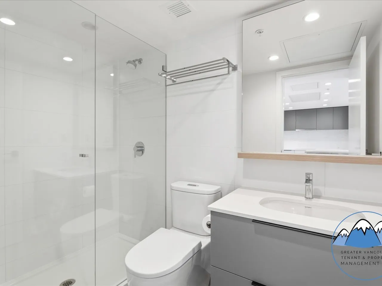 Bathroom with a glass walk-in shower, floating vanity, wide mirror and a pass-through to the kitchen.