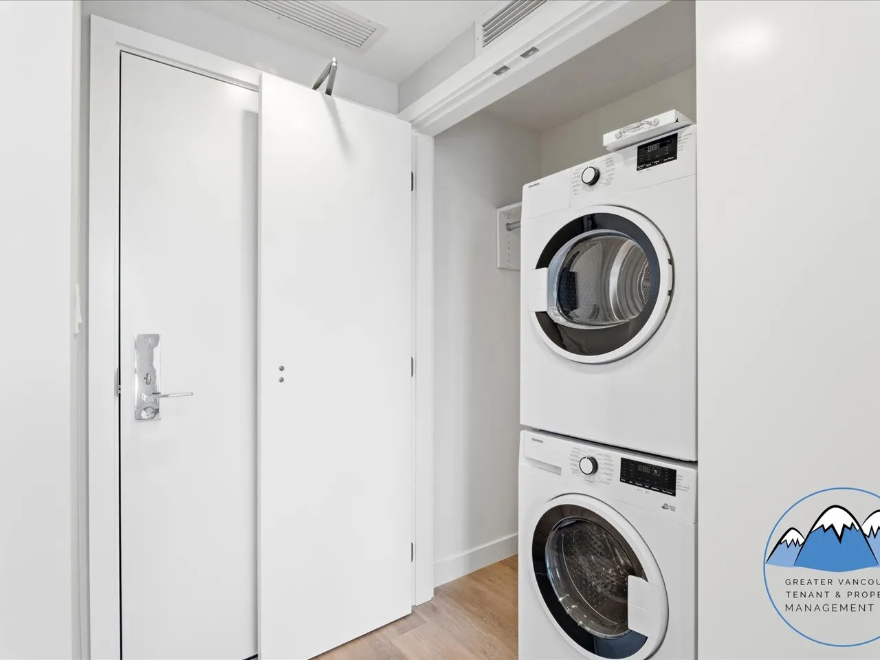 In-unit laundry closet with a stacked washer and dryer beside a sliding door.