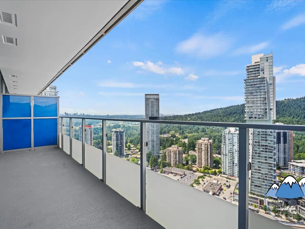The private covered balcony with a glass rail, looking over the city toward distant mountains.