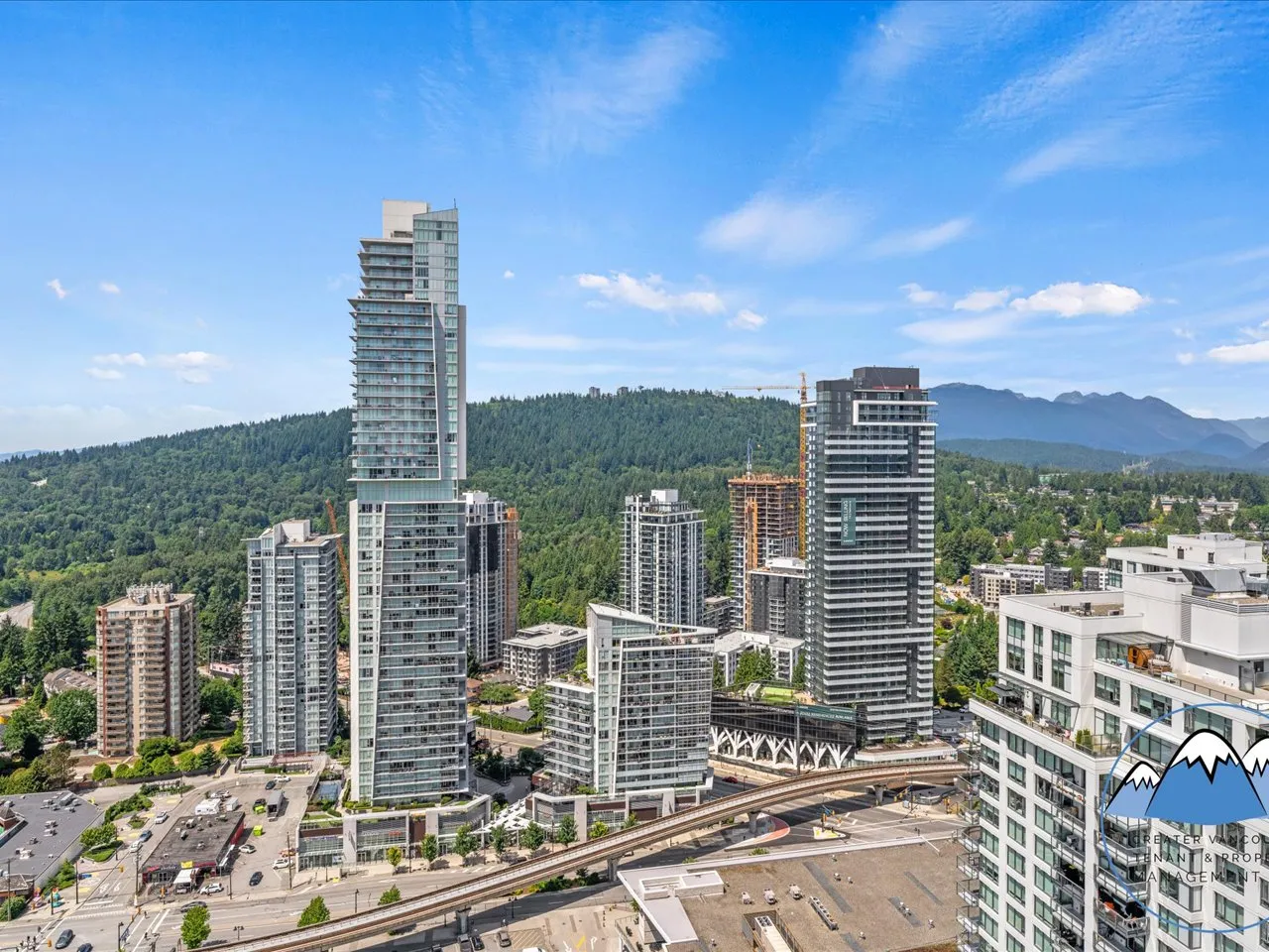 Aerial view of the Burquitlam high-rise cluster set against forested hills.