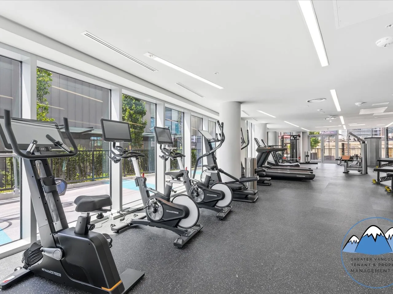 Fitness centre with cardio machines and strength equipment beside floor-to-ceiling windows.