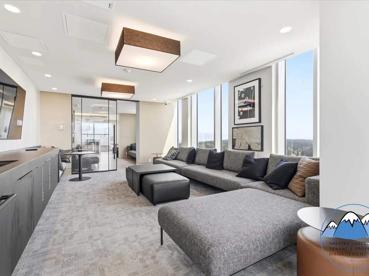Resident lounge with a long kitchen island, soft seating and full-height windows overlooking the surrounding landscape.