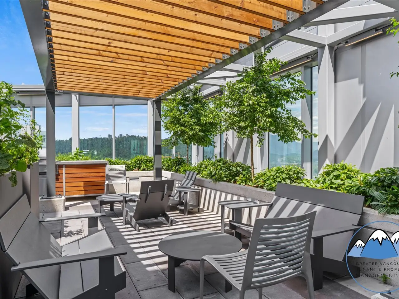 Outdoor rooftop lounge with dining tables, built-in BBQs, a timber canopy and planted seating areas.