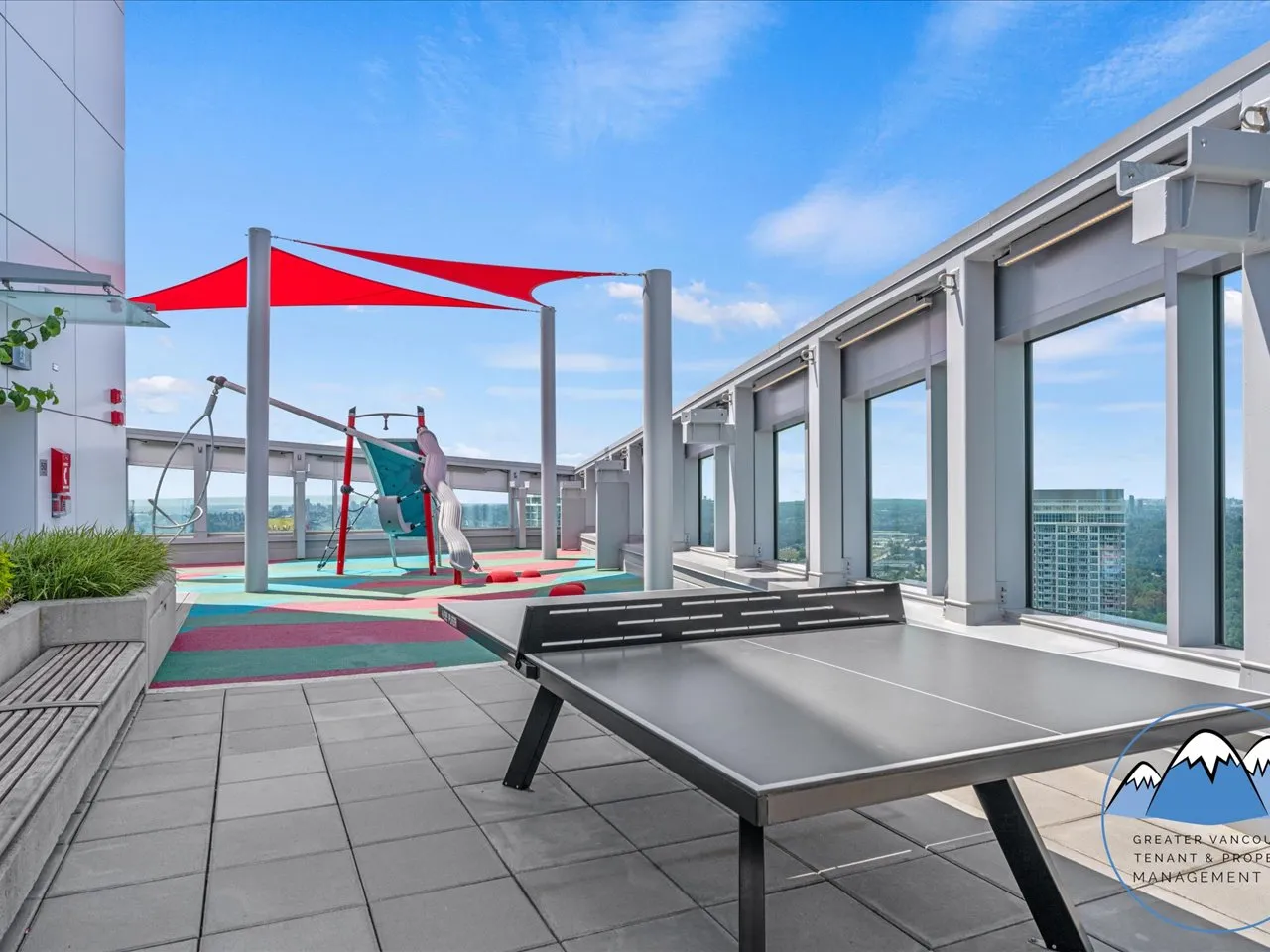 Rooftop play and recreation area with a colourful shade canopy, table tennis and views between the surrounding towers.